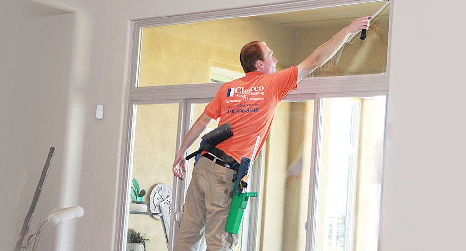 window cleaning technician cleaning an upper window from a step ladder